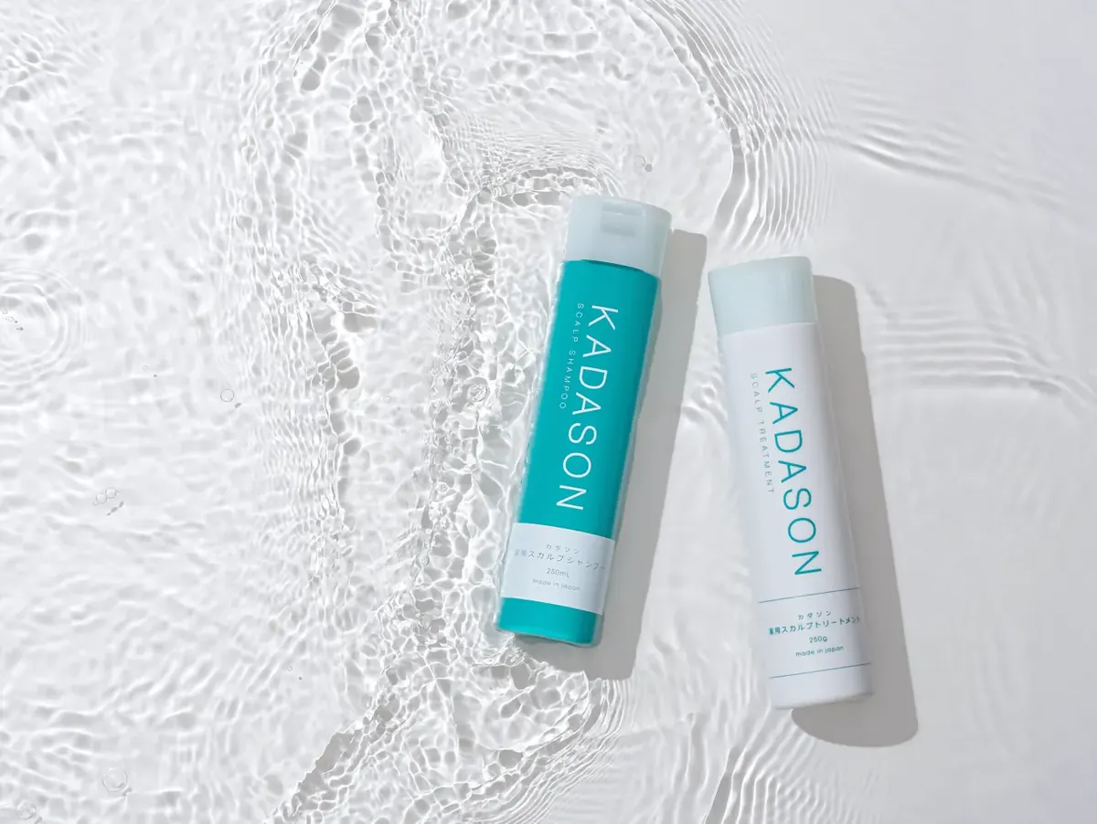 水と自然光の中に置かれたKADASON薬用スカルプシャンプーとトリートメント